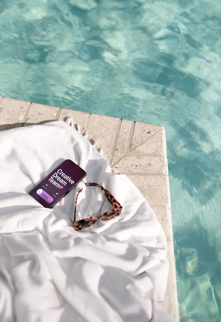 Poolside towel with sunglasses and a phone that reads Creative Dream Team